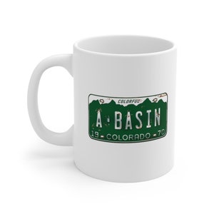 Uma caneca de café Basin, placa de carro do Colorado estilo anos 1970 que diz A Basin, Arapaho Basin, Vintage Antique Automotive Rusty 11 onças
