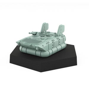 Op de afbeelding: Een lichtgrijs miniatuur tankmodel met een geschutskoepel en twee verticale vinnen. De tank staat op een zwarte, hoekige basis. Het model heeft gedetailleerde kenmerken, waaronder luiken en ventilatieopeningen, en is waarschijnlijk een verzamelobject.