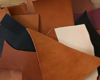 Pode incluir: Conjunto de sobras de couro em várias cores, incluindo marrom, bege, preto e creme. As peças de couro estão dispostas em um padrão aleatório, mostrando diferentes texturas e tons.