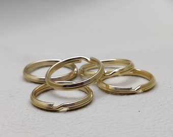 Può includere: Cinque portachiavi in metallo color oro, impilati uno sopra l'altro.
