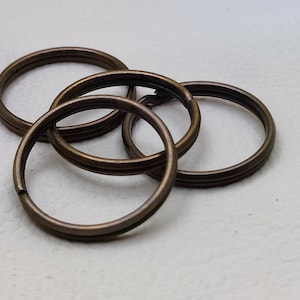 Op de afbeelding: Vier in elkaar grijpende sleutelringen van brons. De ringen zijn allemaal even groot en gemaakt van glad, glanzend metaal.