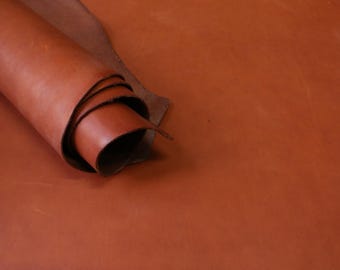 Pode incluir: Um close-up de um rolo de couro marrom. O couro é macio e flexível, e tem um grão natural.