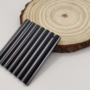 May include: A black metal sheet with a ribbed texture. The sheet has a small hole in the top right corner.