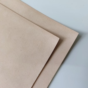 Può includere: Due fogli di carta kraft marrone chiaro impilati uno sopra l'altro.