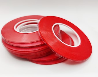 Puede incluir: Un rollo de cinta adhesiva de doble cara roja con un núcleo blanco.