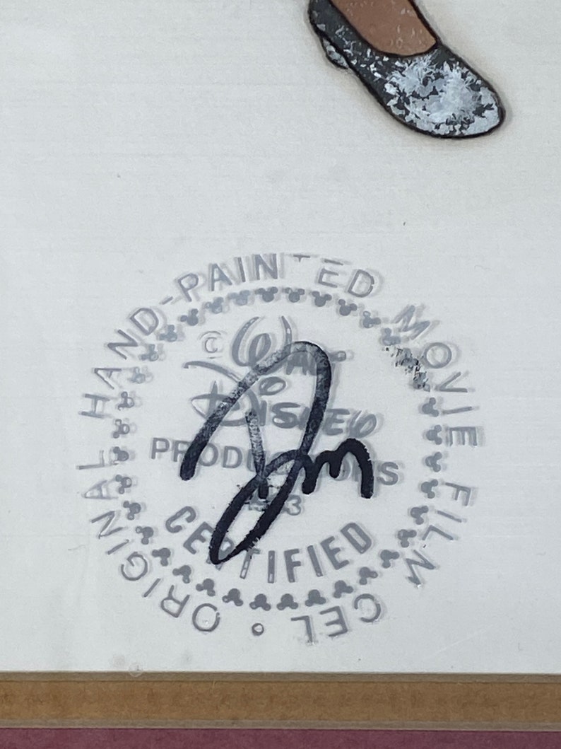 Pu&ograve; includere: Un celluloide di produzione Disney con una firma e un timbro che recita "Original Hand-Painted Movie Film Cel Certified". L'immagine include una scarpa e il logo Disney.