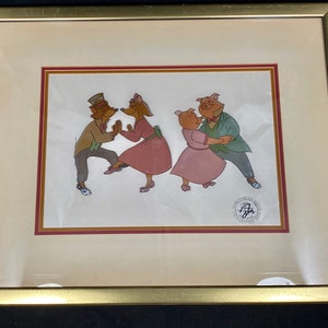 Pu&ograve; includere: Cellula di animazione incorniciata con quattro personaggi dei cartoni animati che ballano. Due sono volpi in abito formale e due sono maiali in abiti rosa e giacche verdi. L'opera d'arte &egrave; ambientata su uno sfondo color crema con una cornice dorata.