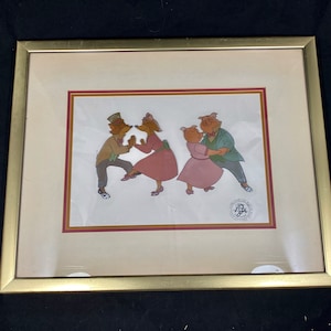May include: Framed artwork featuring cartoon foxes and pigs dancing. The foxes wear hats and dresses, while the pigs are in suits and dresses. The artwork is in a gold frame with a cream-colored mat and a red border.