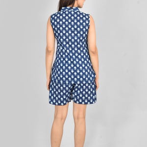 Puede incluir: Conjunto de romper de color azul oscuro con un dise&ntilde;o floral blanco, que consta de una parte superior sin mangas y pantalones cortos. El conjunto presenta un motivo floral repetido. Vista trasera del modelo.