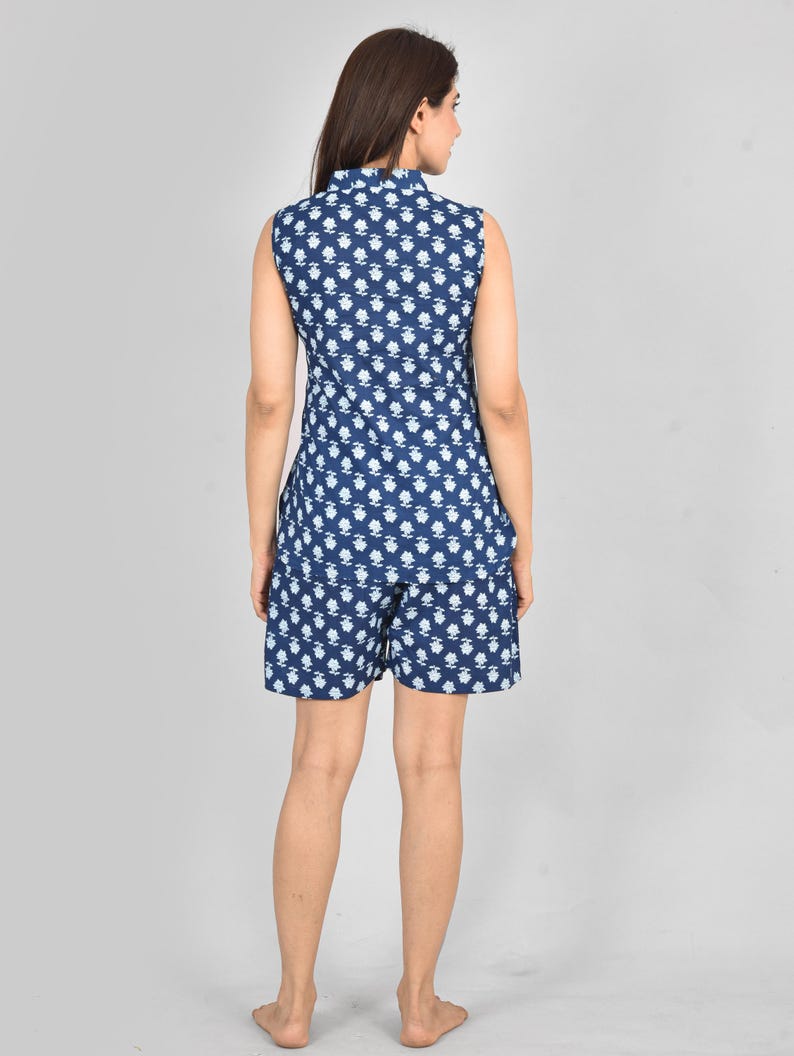 Puede incluir: Conjunto de romper de color azul oscuro con un dise&ntilde;o floral blanco, que consta de una parte superior sin mangas y pantalones cortos. El conjunto presenta un motivo floral repetido. Vista trasera del modelo.