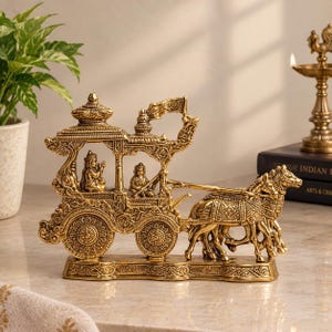 Könnte beinhalten: Eine goldfarbene Messingskulptur, die einen von vier Pferden gezogenen Streitwagen darstellt. Der Wagen weist komplizierte Schnitzereien, ein Vordach und zwei sitzende Figuren im Inneren auf. Das Stück steht auf einem rechteckigen Sockel.