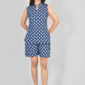 Puede incluir: Conjunto de pijama de dos piezas sin mangas, azul marino y blanco con estampado floral. La parte superior tiene cuello mandar&iacute;n y los pantalones cortos tienen bolsillos. La tela parece ligera y c&oacute;moda.