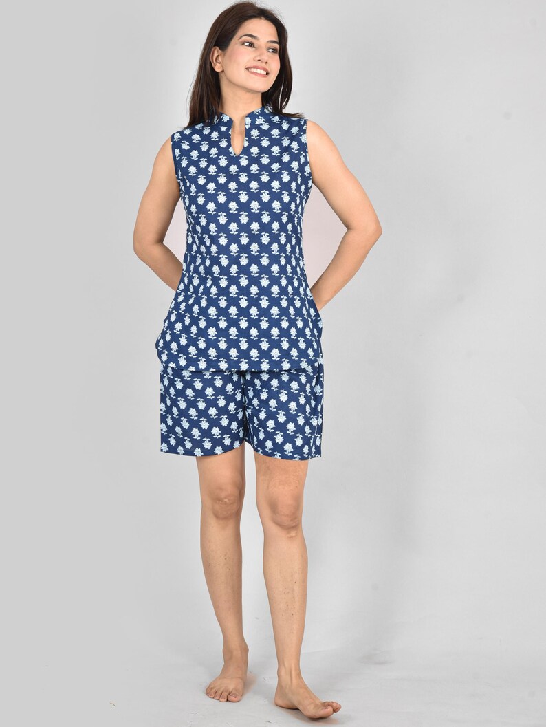 Puede incluir: Conjunto de pijama de dos piezas sin mangas, azul marino y blanco con estampado floral. La parte superior tiene cuello mandar&iacute;n y los pantalones cortos tienen bolsillos. La tela parece ligera y c&oacute;moda.
