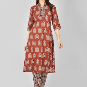 May include: A rust-coloured kurta set with a repeating geometric pattern in teal and white. The kurta has a mandarin collar and three-quarter sleeves. The matching trousers have a contrasting pattern in shades of brown and black. A stylish and comfortable outfit.