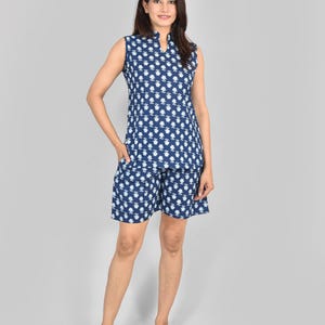 Puede incluir: Conjunto de pijama azul marino con estampado floral blanco. El conjunto incluye una camiseta sin mangas con cuello mandar&iacute;n y pantalones cortos a juego. La tela parece ligera, ideal para ropa de dormir o informal. Medidas en cent&iacute;metros.
