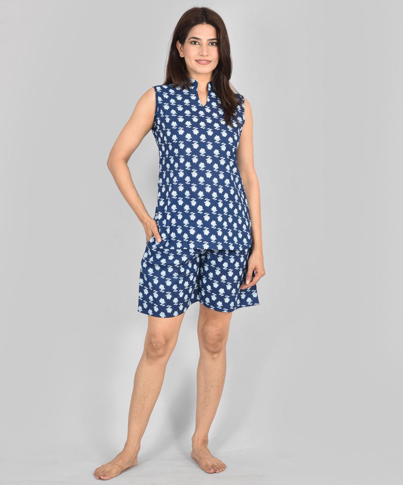Puede incluir: Conjunto de pijama azul marino con estampado floral blanco. El conjunto incluye una camiseta sin mangas con cuello mandar&iacute;n y pantalones cortos a juego. La tela parece ligera, ideal para ropa de dormir o informal. Medidas en cent&iacute;metros.