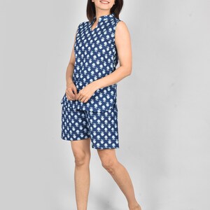 Puede incluir: Un conjunto de pijama azul marino sin mangas con un estampado floral blanco. La parte superior tiene un cuello mandar&iacute;n y una abertura en V. Los pantalones cortos a juego completan el conjunto. La tela parece ligera y c&oacute;moda.