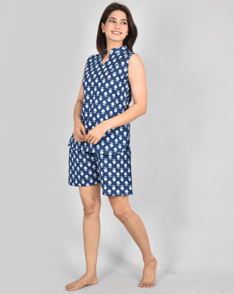 Puede incluir: Un conjunto de pijama azul marino sin mangas con un estampado floral blanco. La parte superior tiene un cuello mandar&iacute;n y una abertura en V. Los pantalones cortos a juego completan el conjunto. La tela parece ligera y c&oacute;moda.