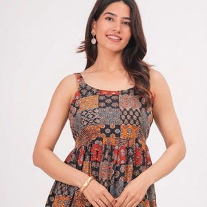 Könnte beinhalten: Ein ärmelloses Oberteil mit Patchwork-Design, das verschiedene florale und geometrische Muster in den Farben Schwarz, Orange, Rot und Grau aufweist. Das Kleidungsstück hat einen Rundhalsausschnitt, breite Träger und eine geraffte Taille.
