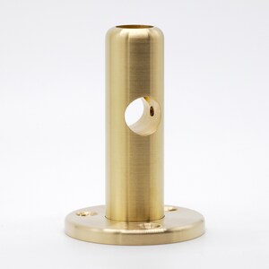 May include: A gold metal pipe fitting with a round base and a hole in the center. The pipe fitting is designed to be used for connecting pipes or other plumbing fixtures.