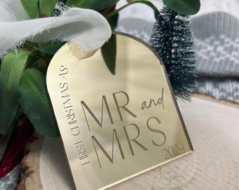 May include: Gold mirrored Christmas ornament with the text "First Christmas as Mr and Mrs 2024".