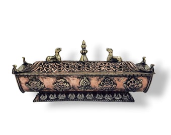 Peut inclure: Un brûleur d'encens en cuivre avec des sculptures complexes et des accents dorés. Le brûleur a une forme rectangulaire avec une base surélevée et trois figures animales décoratives sur le dessus.