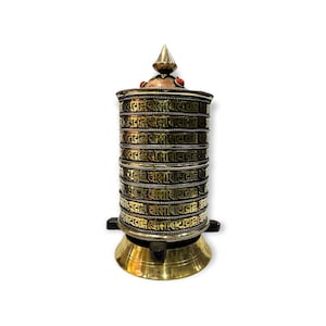 May include: A gold prayer wheel with a pointed top and red accents. The wheel is decorated with intricate patterns and Tibetan script.