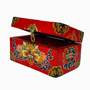 May include: A red wooden box with a gold latch and intricate painted designs. The box is open and the inside is lined with red velvet.