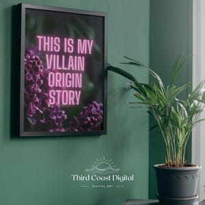 May include: Framed art print with the text "THIS IS MY VILLAIN ORIGIN STORY" in pink neon against a dark background with purple flowers. The print is in a black frame and hangs on a teal wall.