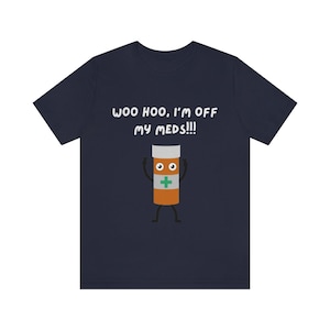 Puede incluir: Camiseta azul marino con un gráfico blanco de un frasco de píldoras con ojos y brazos, y el texto "WOO HOO, I'M OFF MY MEDS!!!"