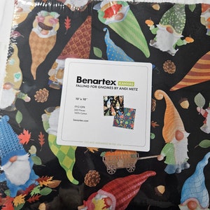 May include: A fabric bundle featuring a repeating pattern of colorful gnomes, autumn leaves, and pinecones on a black background. The label reads "Falling for Gnomes by Andi Metz" and indicates the fabric is 10" x 10" squares.