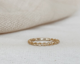 May include: A gold-toned twisted band ring. The ring is simple and delicate, with a smooth, polished finish.