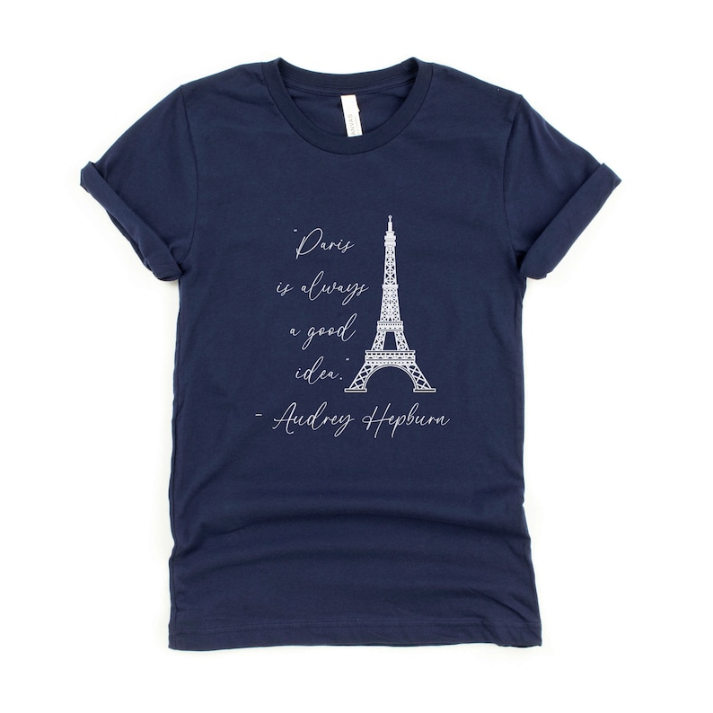 K&ouml;nnte beinhalten: Marineblaues T-Shirt mit einem wei&szlig;en Grafikdruck des Eiffelturms und dem Zitat "Paris ist immer eine gute Idee. - Audrey Hepburn".