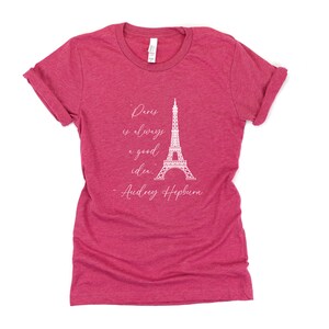 K&ouml;nnte beinhalten: Ein rotes T-Shirt mit einer wei&szlig;en Grafik des Eiffelturms und dem Zitat "Paris ist immer eine gute Idee." - Audrey Hepburn.
