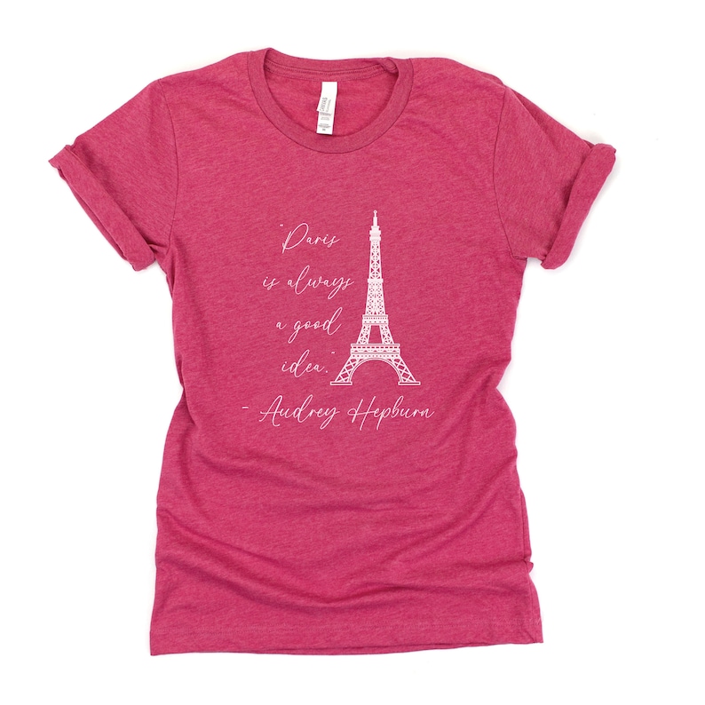 K&ouml;nnte beinhalten: Ein rotes T-Shirt mit einer wei&szlig;en Grafik des Eiffelturms und dem Zitat "Paris ist immer eine gute Idee." - Audrey Hepburn.