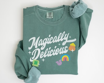 May include: A teal green sweatshirt with the text "Magically Delicious" in white with a rainbow, a shamrock, and a pot of gold graphic.