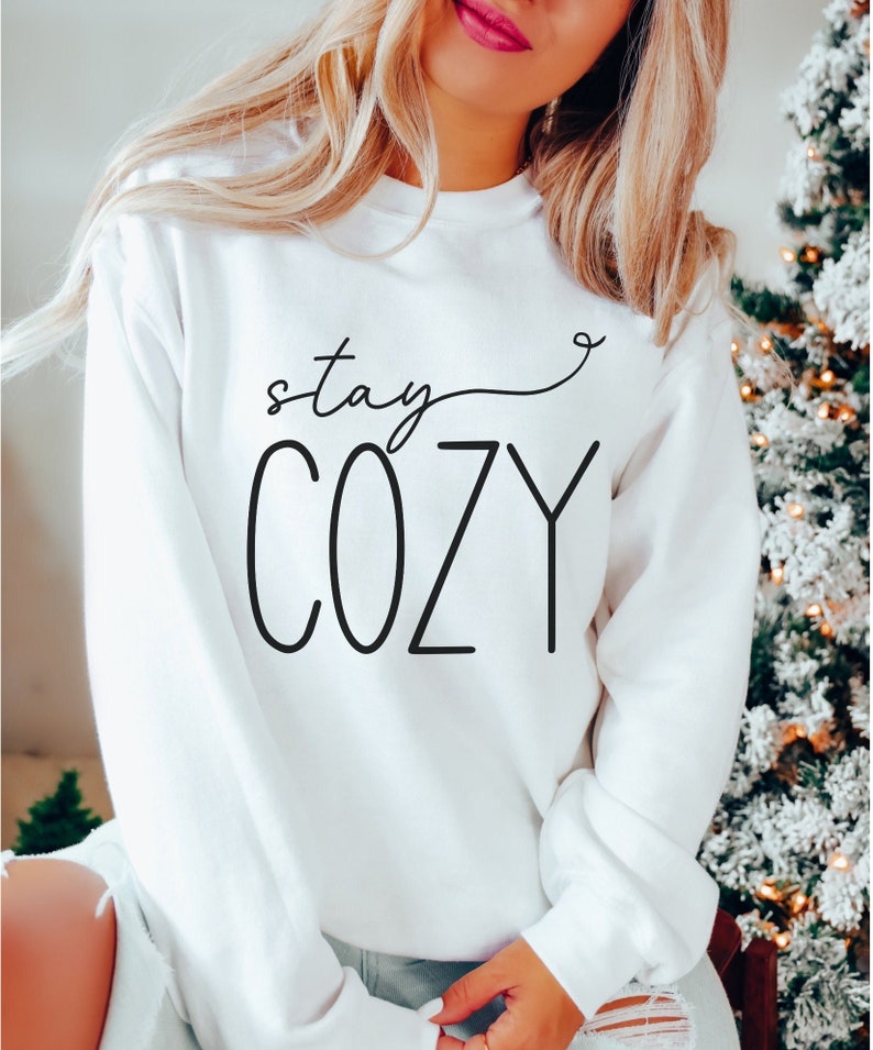 May include: White sweatshirt with black text that reads "stay cozy" with a heart symbol.