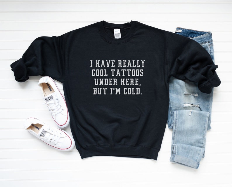 May include: Black sweatshirt with the text "I have really cool tattoos under here, but I'm cold."