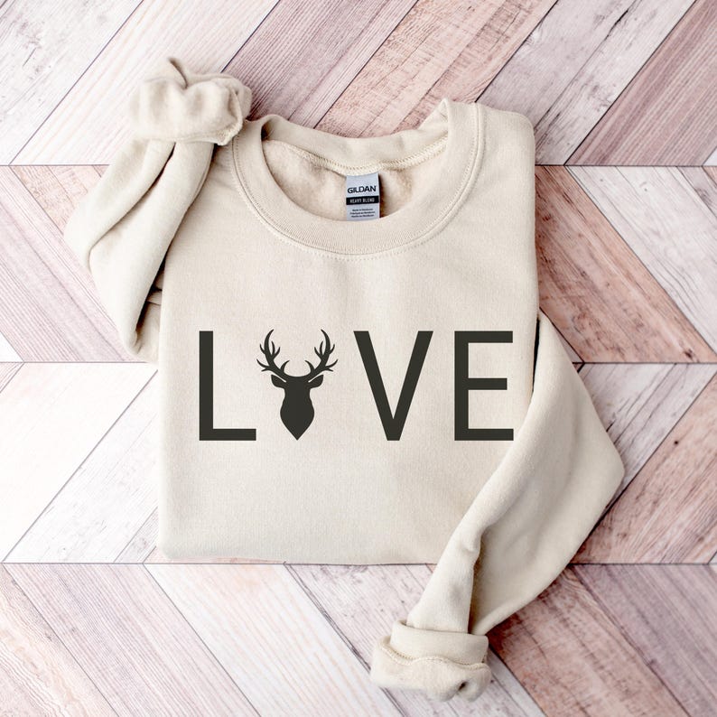 May include: A beige sweatshirt with the word "LOVE" printed in black with a deer silhouette in the middle of the word.