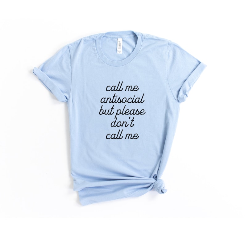 May include: Light blue t-shirt with black text that reads "call me antisocial but please don't call me".