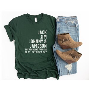 May include: A dark green t-shirt with white text that reads "Jack Jim Johnny & Jameson The Founding Fathers of St. Patrick's Day".