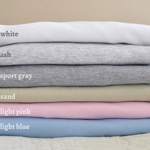 Puede incluir: Pila de seis camisetas de diferentes colores: blanco, ceniza, gris deportivo, arena, rosa claro y azul claro.