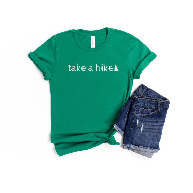 May include: A green t-shirt with the text "take a hike" and a small pine tree graphic printed in white.