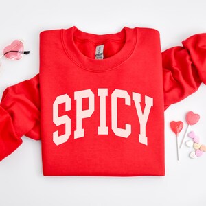 K&ouml;nnte beinhalten: Roter Pullover mit dem Wort "SPICY" in Wei&szlig; auf der Vorderseite.