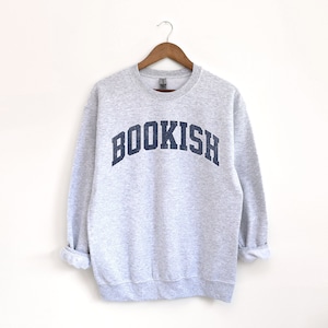 May include: Gray sweatshirt with a navy blue arch design that says "BOOKISH".