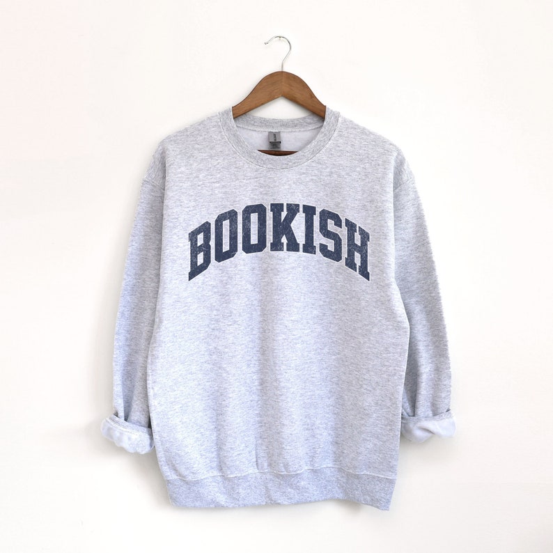 May include: Gray sweatshirt with a navy blue arch design that says "BOOKISH".
