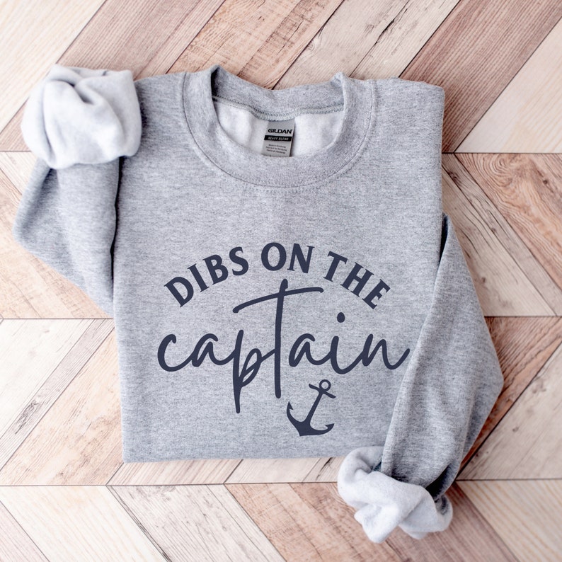 Puede incluir: Sudadera gris con el texto "Dibs on the captain" en letras negras con un s&iacute;mbolo de ancla debajo.