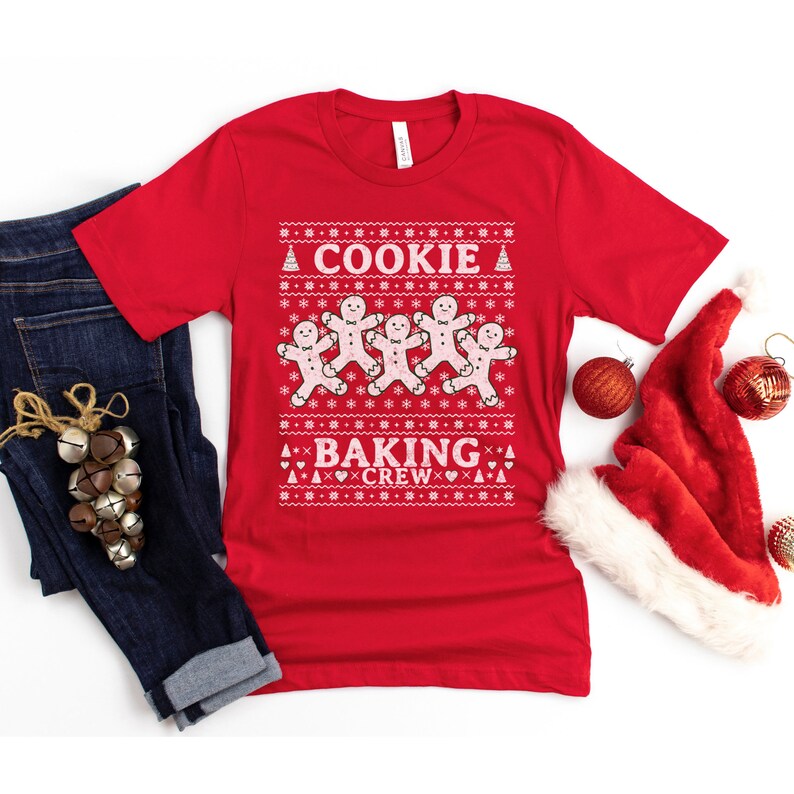 May include: Red Christmas sweater with a white gingerbread man design and the text "Cookie Baking Crew".
