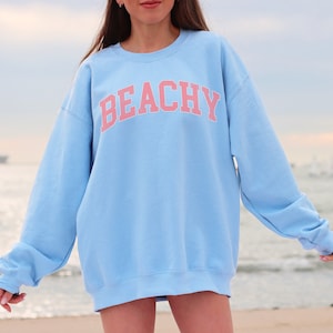 May include: A light blue sweatshirt with the word "BEACHY" printed in pink letters.
