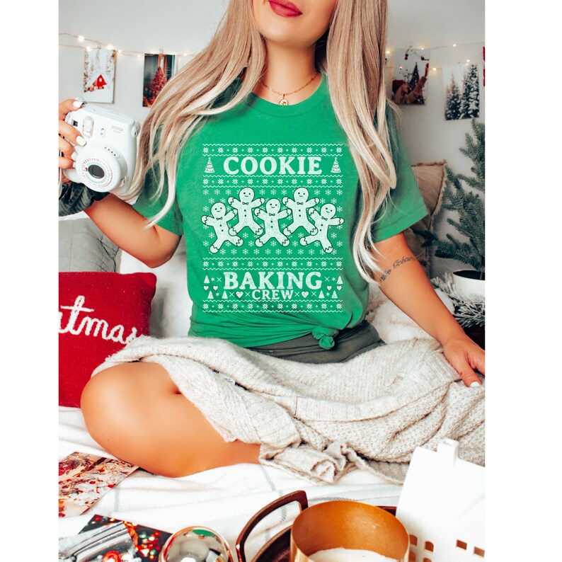 May include: Green Christmas sweater with a white gingerbread man design and the text "Cookie Baking Crew".